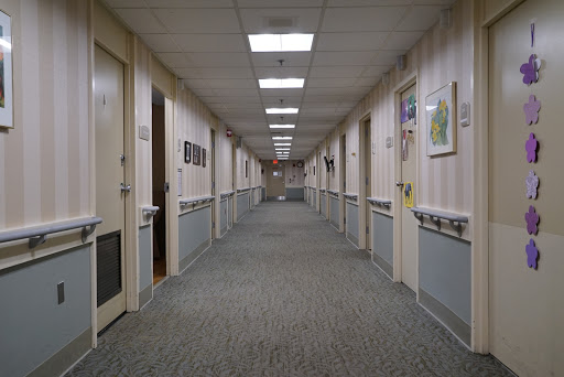A long, well-lit corridor featuring multiple doors on both sides.