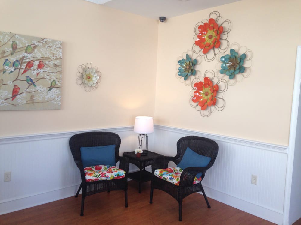 A cozy seating area with two wicker chairs, a small table, and colorful wall art.