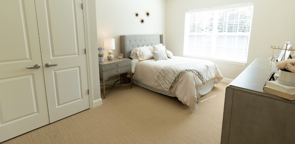 A cozy and well-decorated bedroom with a comfortable bed, nightstand, and soft carpet.