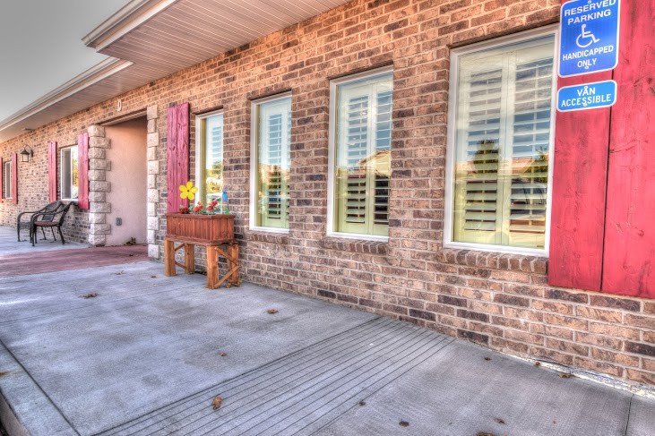 A brick house exterior with large windows, shutters, and a patio adorned with a flower box.