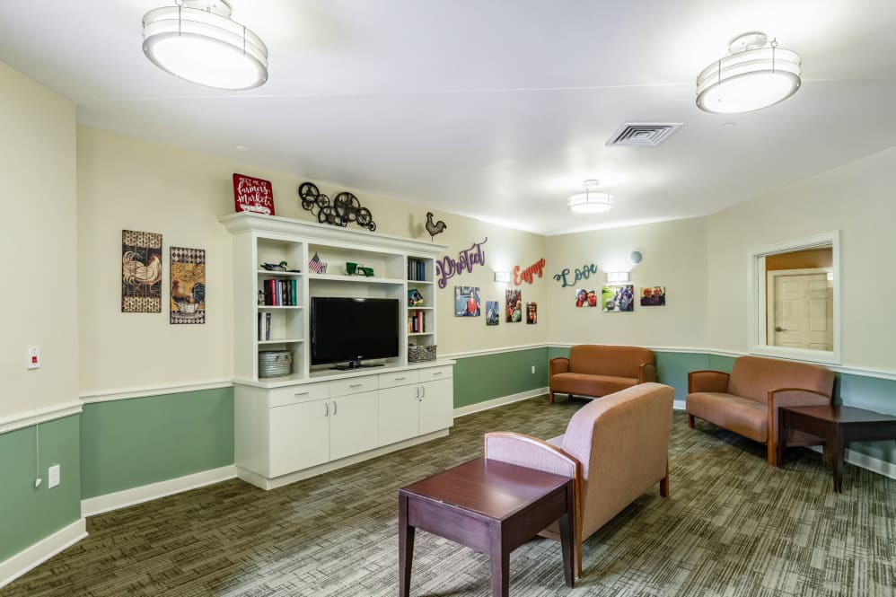 A cozy community living room with seating, a television, and decorative elements on the walls.