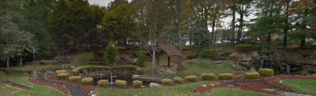 A scenic view of a garden with lush greenery and a small wooden structure.