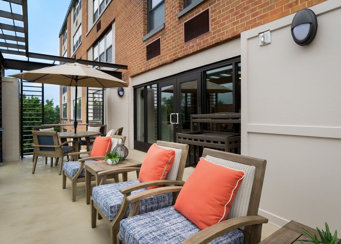 A cozy outdoor patio with cushioned chairs and an umbrella for shade.