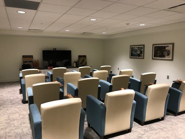 A small theater room with multiple rows of chairs facing a large screen.