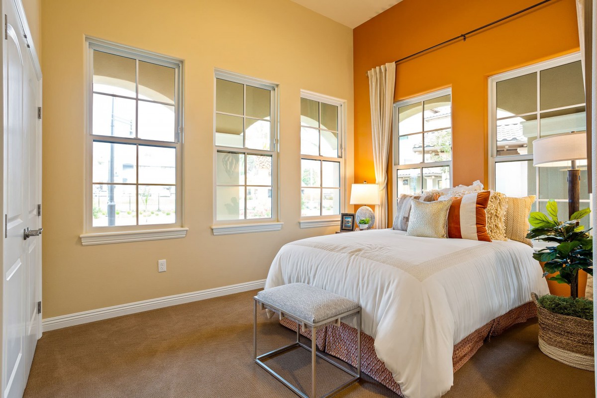 A modern bedroom with large windows and warm-colored walls.