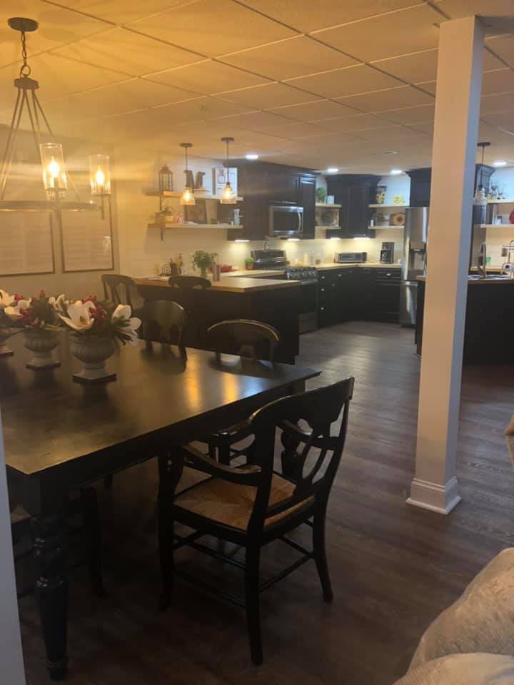 Modern kitchen and dining area with dark wood furniture and dim lighting.