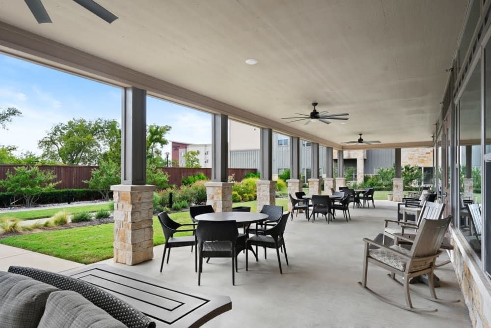A spacious outdoor patio with tables and chairs, overlooking a landscaped garden.