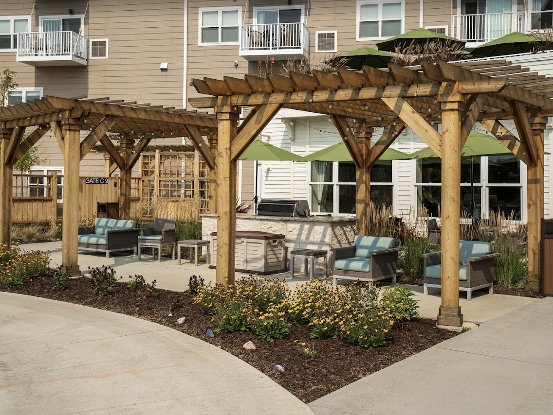 A cozy outdoor patio area with pergolas, seating, and landscaping at an apartment complex.
