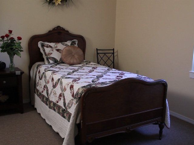 A cozy bedroom with a single bed featuring a decorative quilt and wooden headboard.