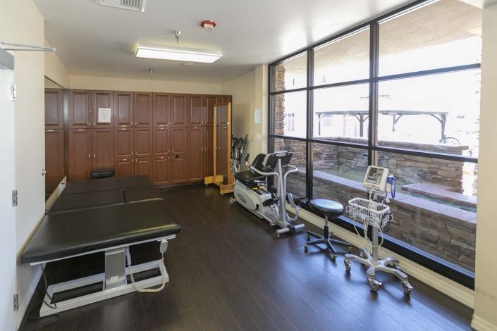 A well-equipped physical therapy room with exercise machines and therapy tables.