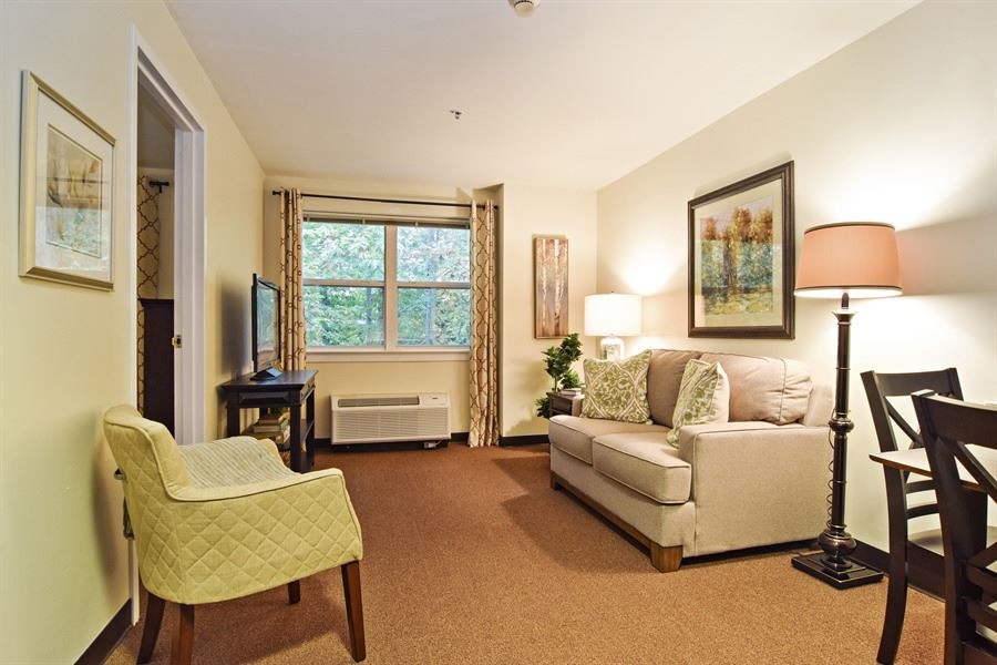 A cozy living room with a sofa, chair, lamp, and artwork on the walls.