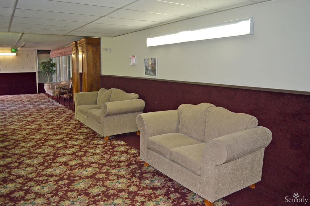 A hallway with beige couches and patterned carpet.