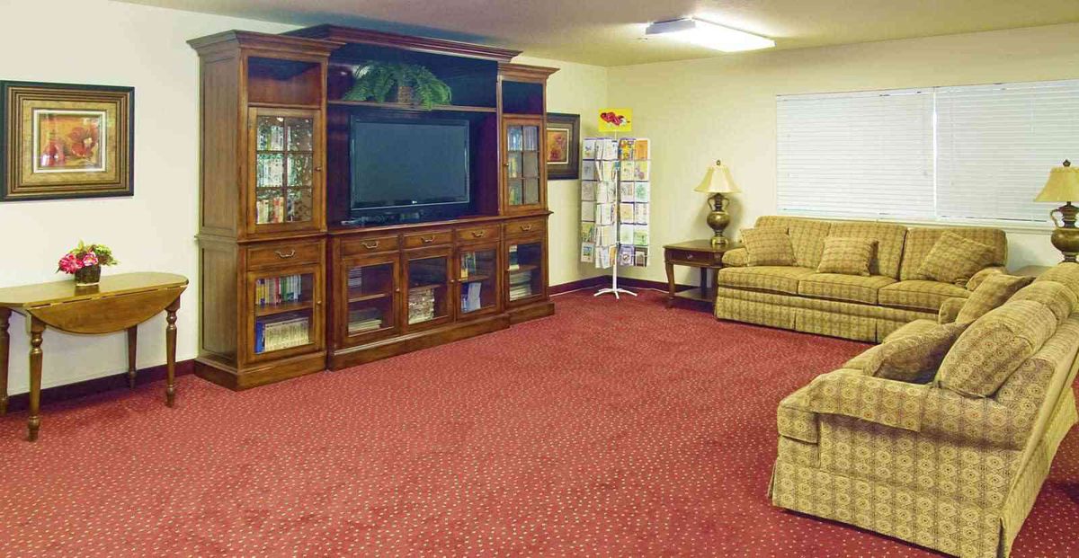 A cozy living room featuring an entertainment center with a television, a sofa, and a red carpet.