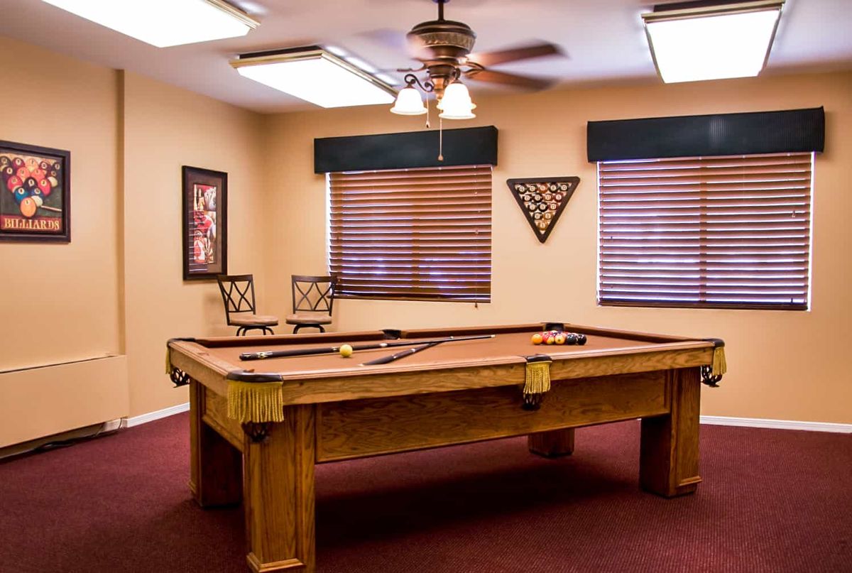 A cozy billiard room featuring a pool table, ceiling fan, and stylish wall decor.