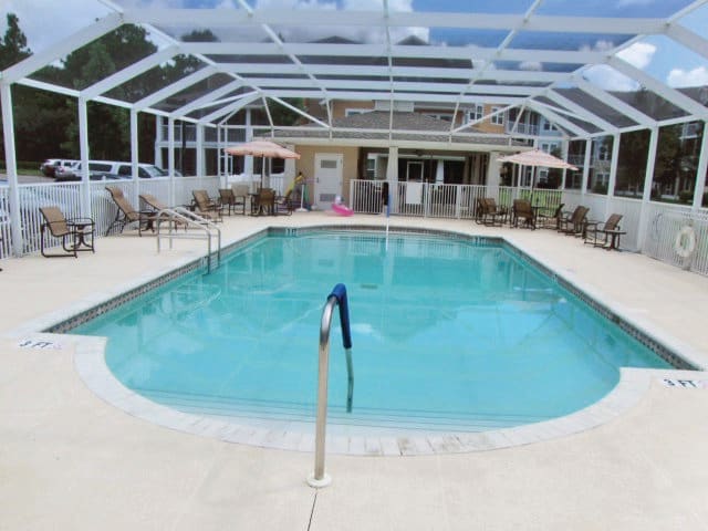 An enclosed outdoor swimming pool with surrounding patio furniture.