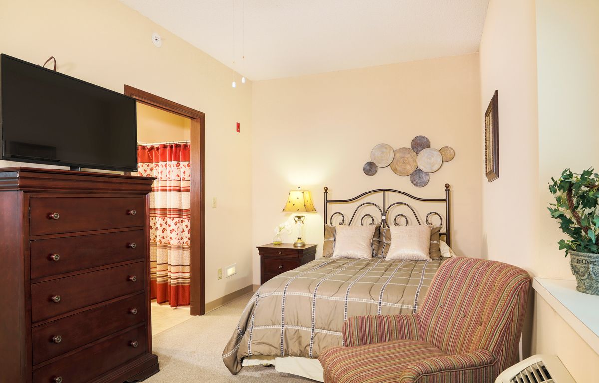 Cozy bedroom with a bed, dresser, and decorative elements.
