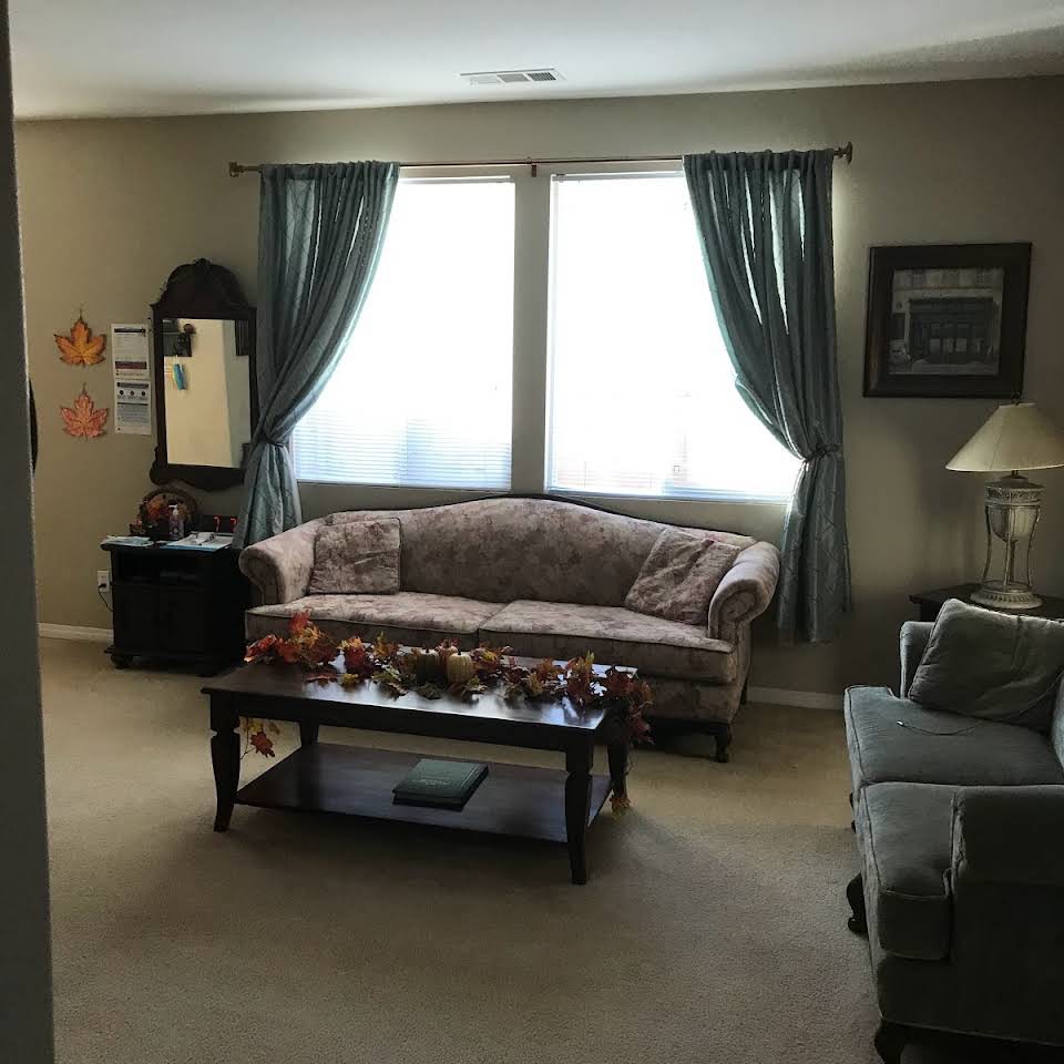 A cozy living room with a sofa, coffee table, and curtains by the window.