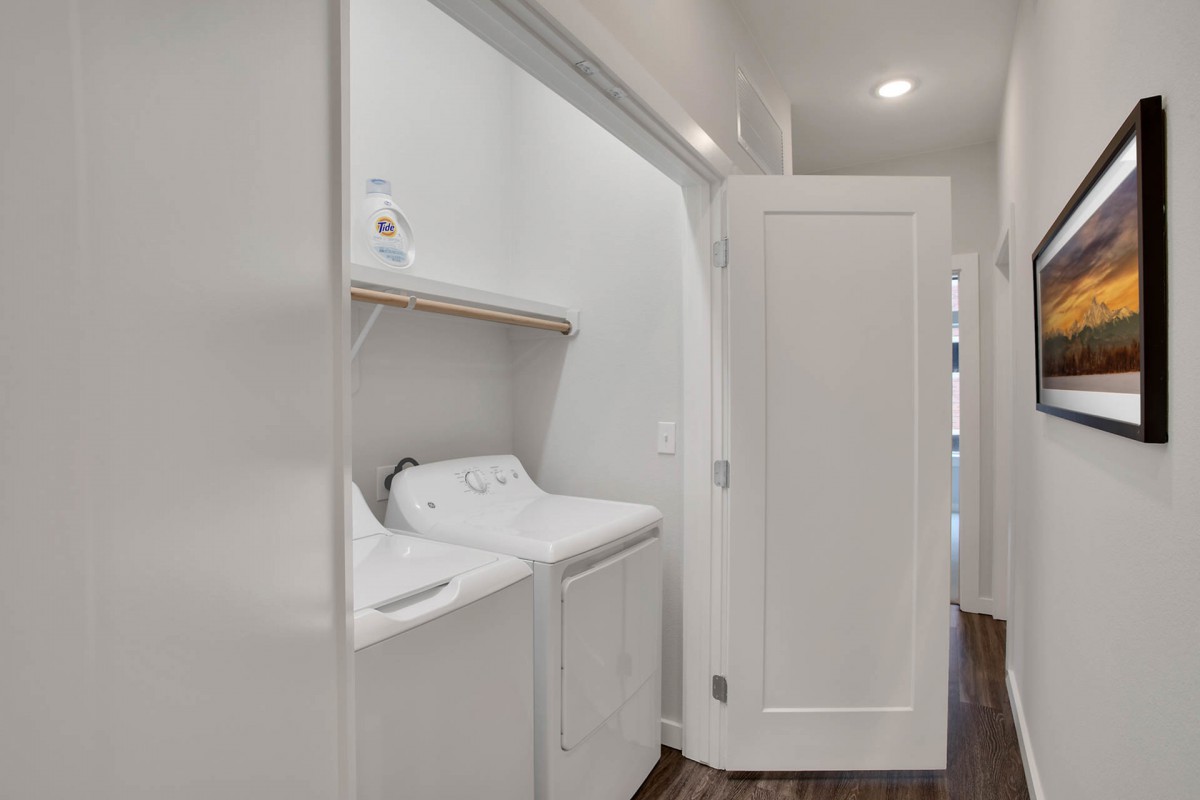 A compact laundry area with a washer and dryer, featuring shelving for storage.