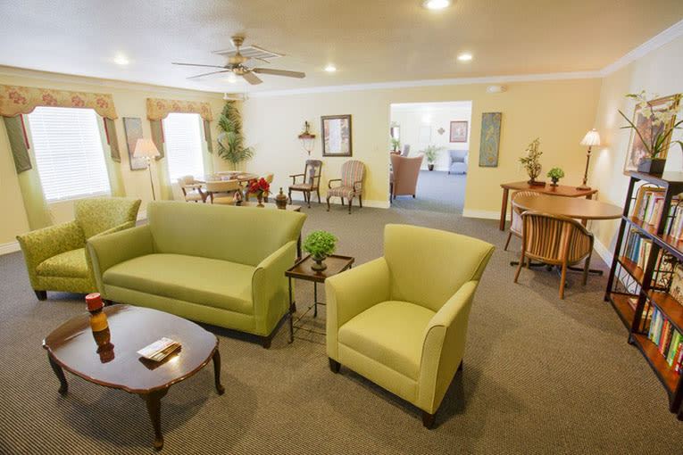 A cozy living room with green sofas and armchairs, complemented by warm lighting and tasteful decor.