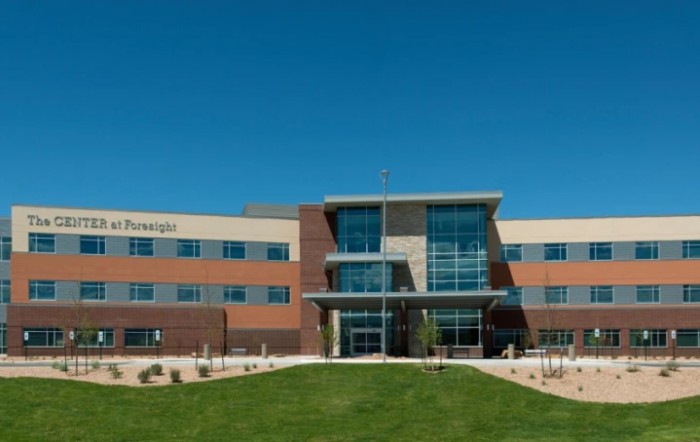 A modern office building with a glass facade under a clear blue sky.