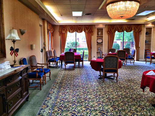 A cozy lounge area featuring a floral carpet, elegant furniture, and ample natural light.