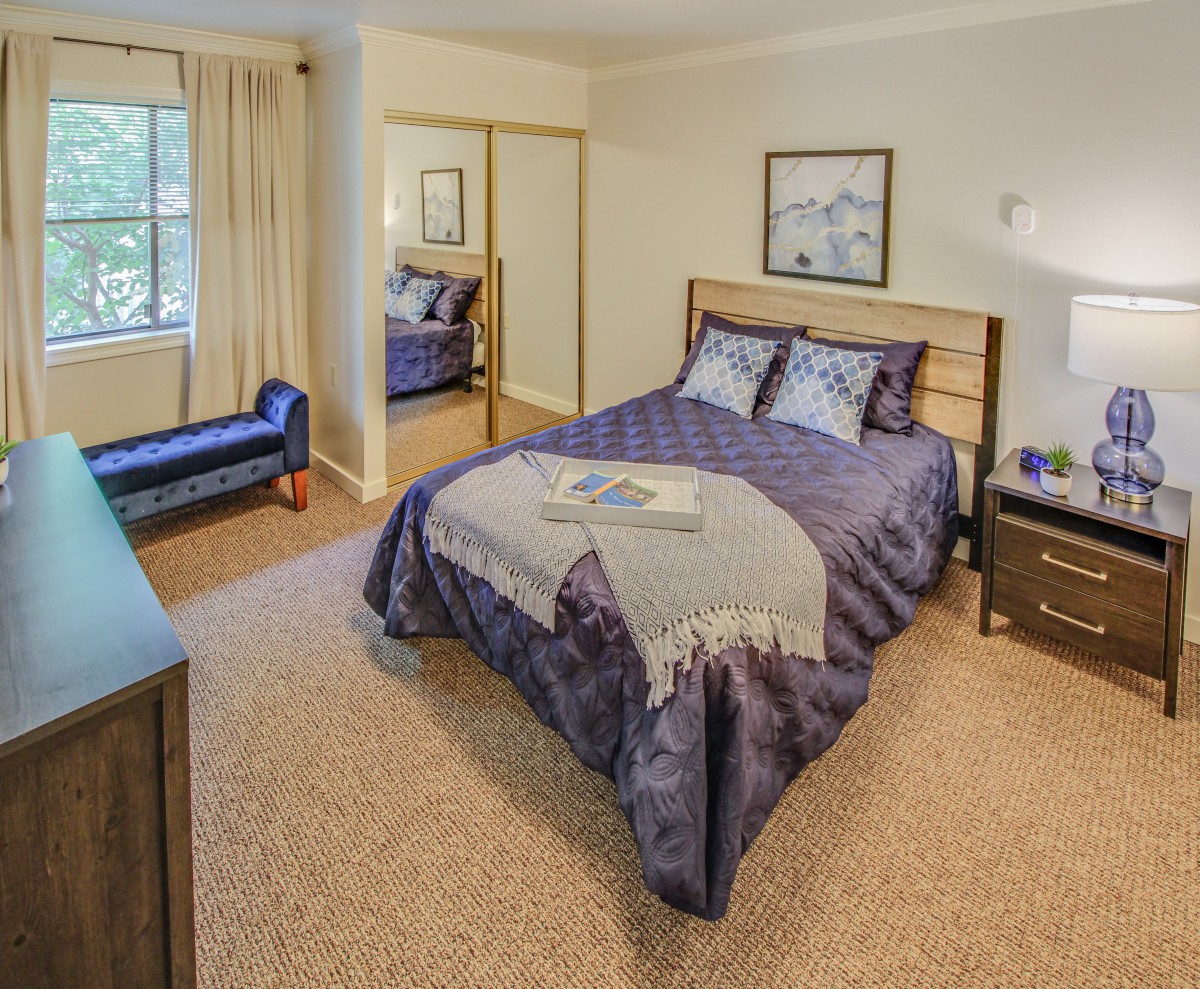 A cozy bedroom with a neatly made bed, mirror closet, and elegant decor.