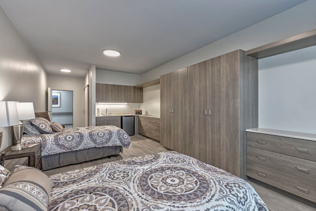 A modern bedroom with two beds and a large wardrobe.