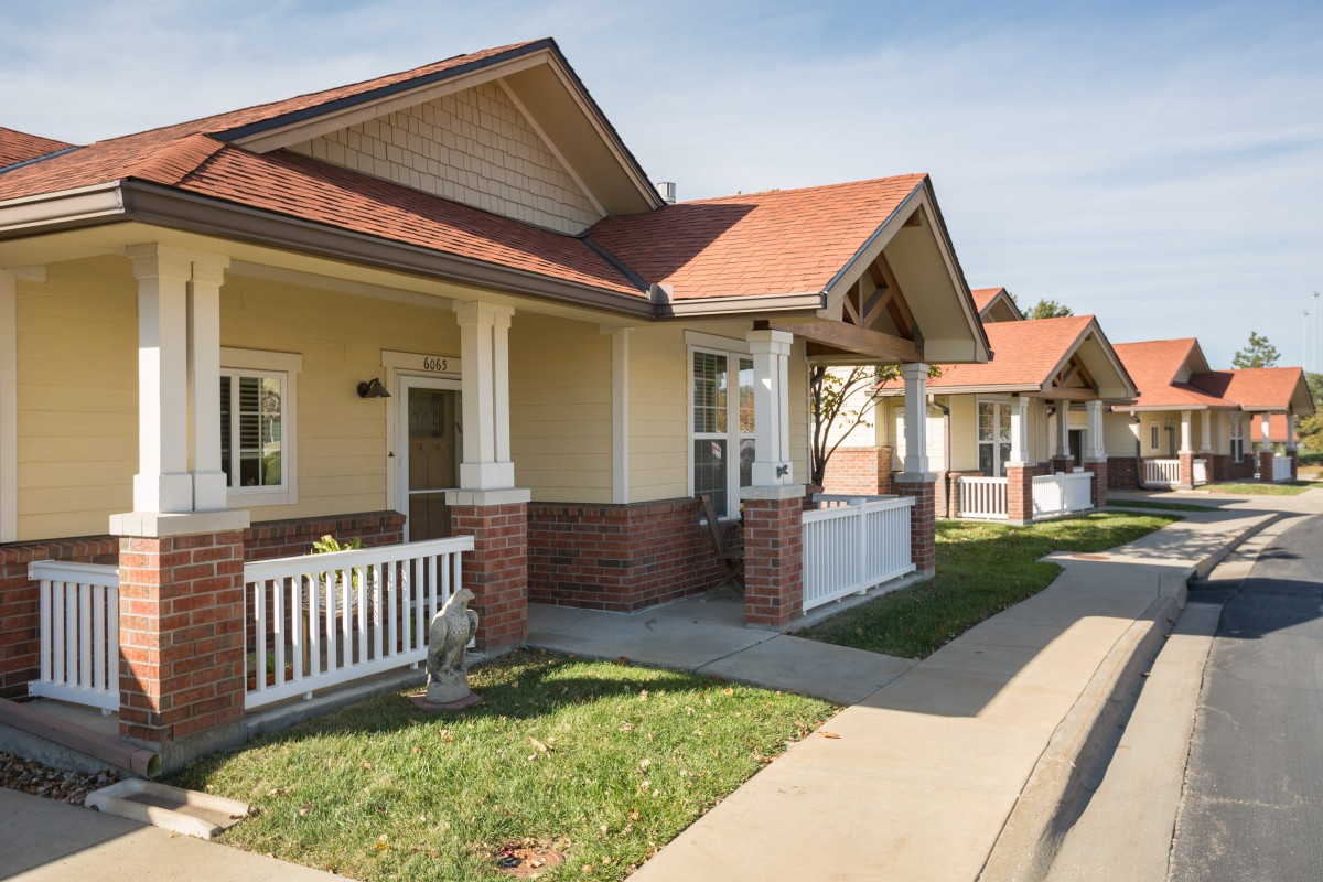 A row of suburban houses with porches and manicured lawns.