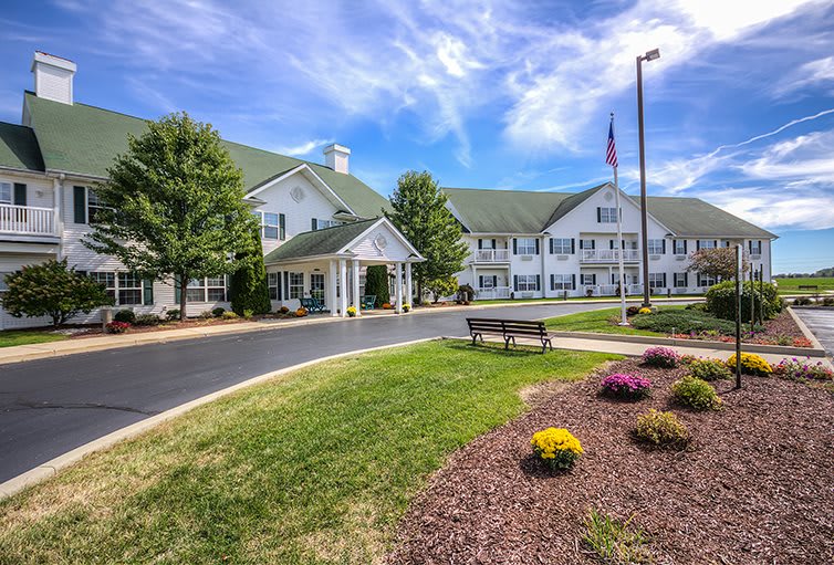 A well-maintained building with a landscaped garden and driveway under a vibrant blue sky.