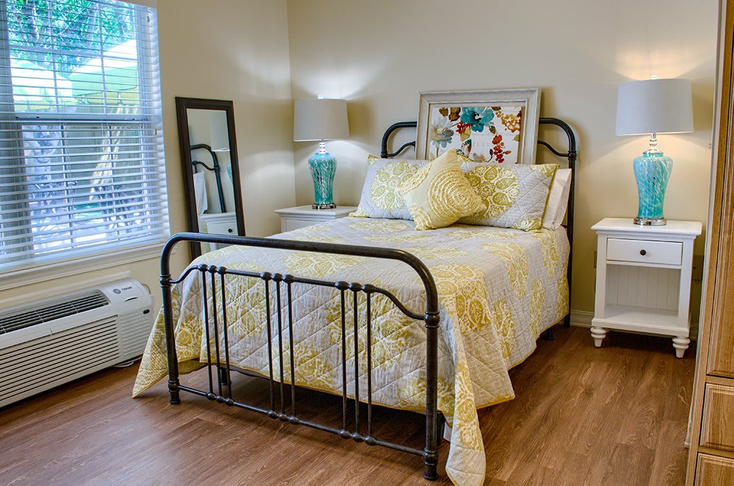 A cozy bedroom with a metal bed frame, decorated in yellow and floral patterns.