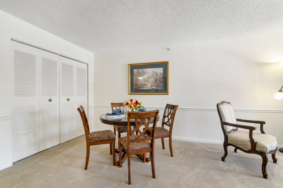 A cozy dining area with a round table, four chairs, and wall artwork.