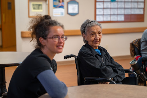 A young woman and an elderly woman engage in conversation at a community center.