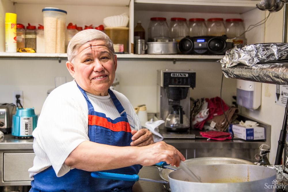 A chef in a kitchen stirring a pot.