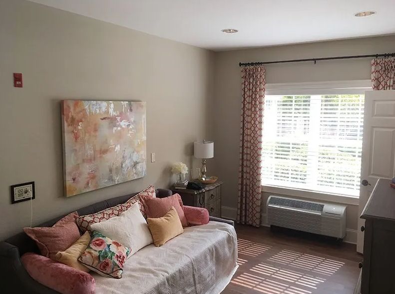A cozy living room with a sofa, artwork on the wall, and sunlight streaming through the window.