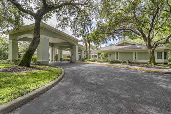 A scenic view of a building entrance surrounded by trees and lush landscaping.