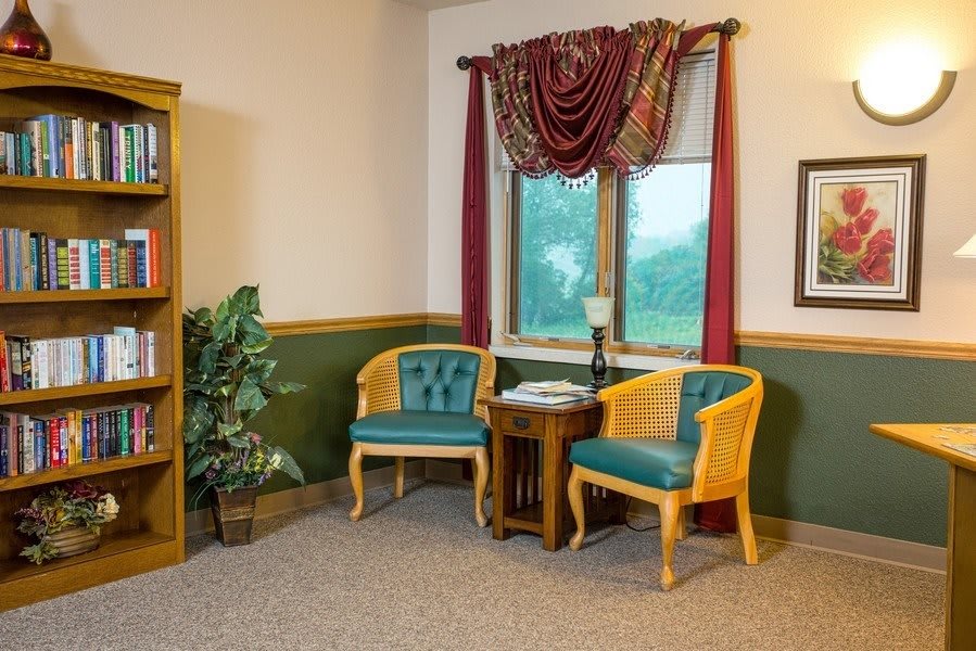 A cozy corner with two chairs and a small table near a window, adorned with curtains.