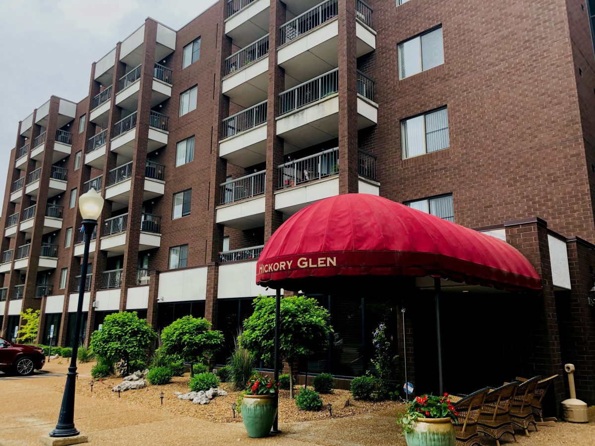 A residential apartment building with a red awning entrance.