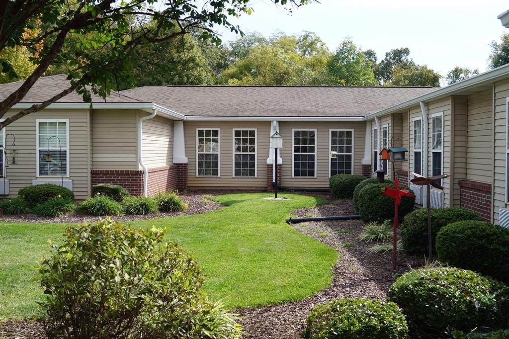 A well-maintained garden with a central lawn surrounded by a residential building.