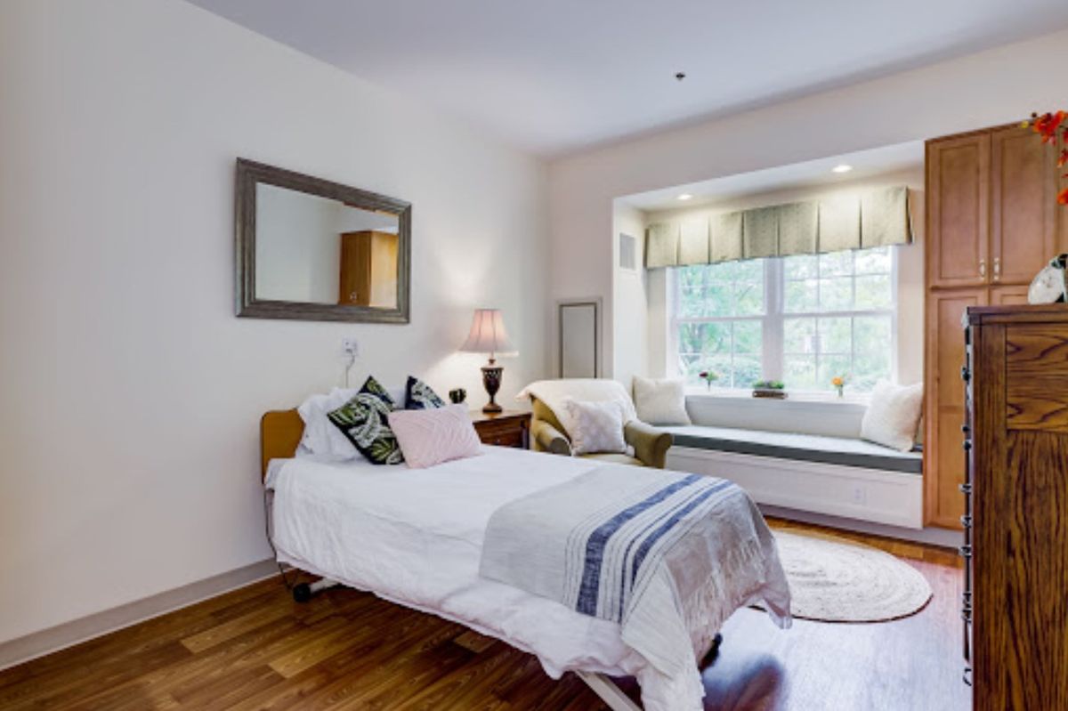 A cozy bedroom with a single bed, decorative pillows, and a window seat.
