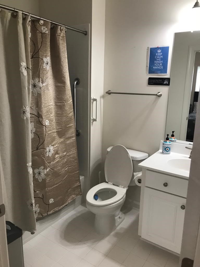 A clean and simple bathroom with a toilet, sink, and shower area.