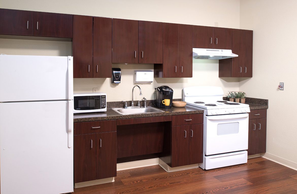 A modern kitchen with dark wood cabinets, a white stove, refrigerator, microwave, and a sink.