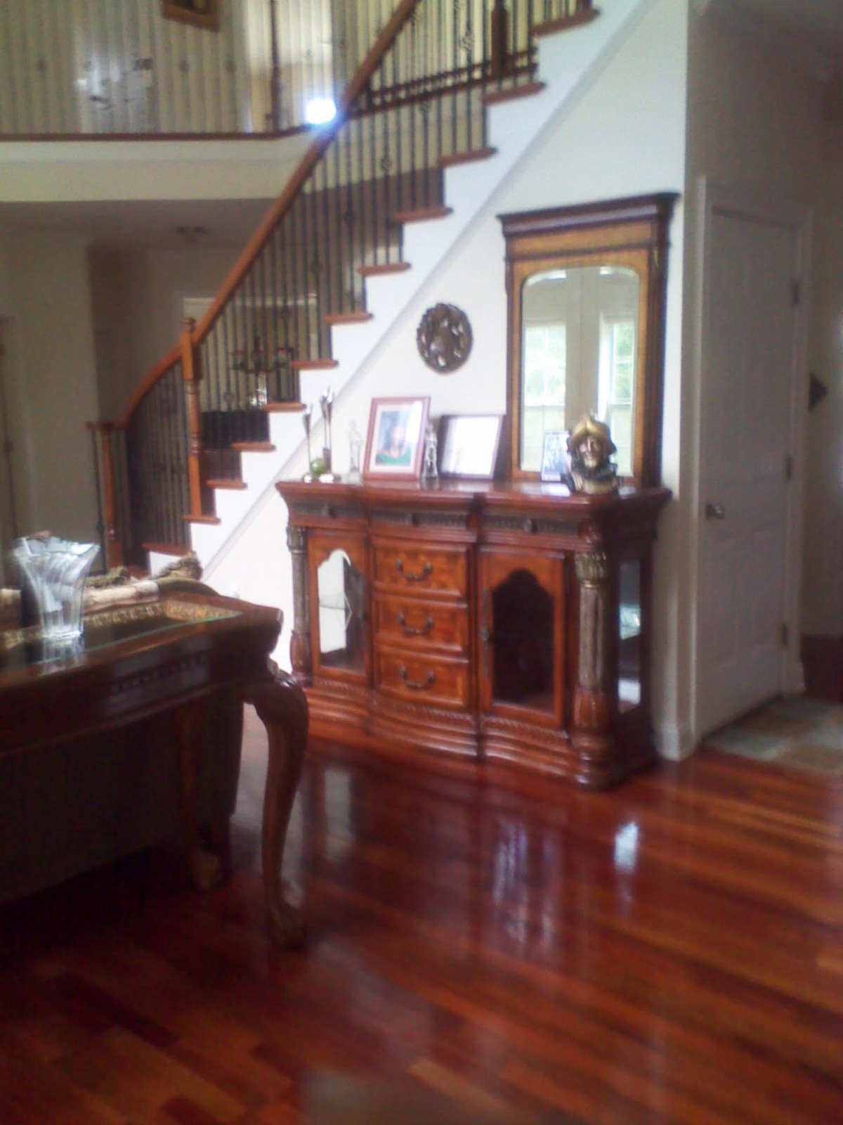 A cozy living room with a wooden staircase and polished hardwood floors.