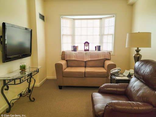 A cozy living room setup featuring a beige sofa, an armchair, and a television.
