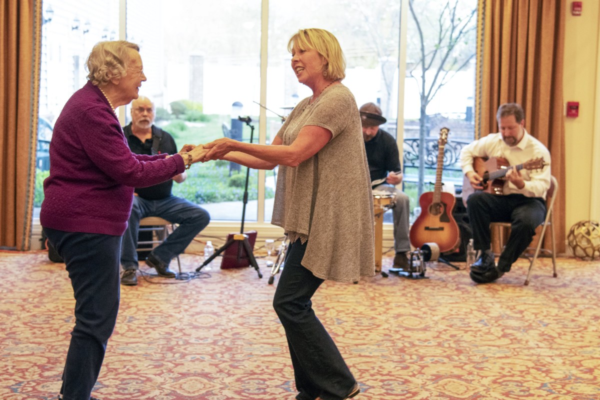 Two women enjoy dancing together while a live band plays in the background.