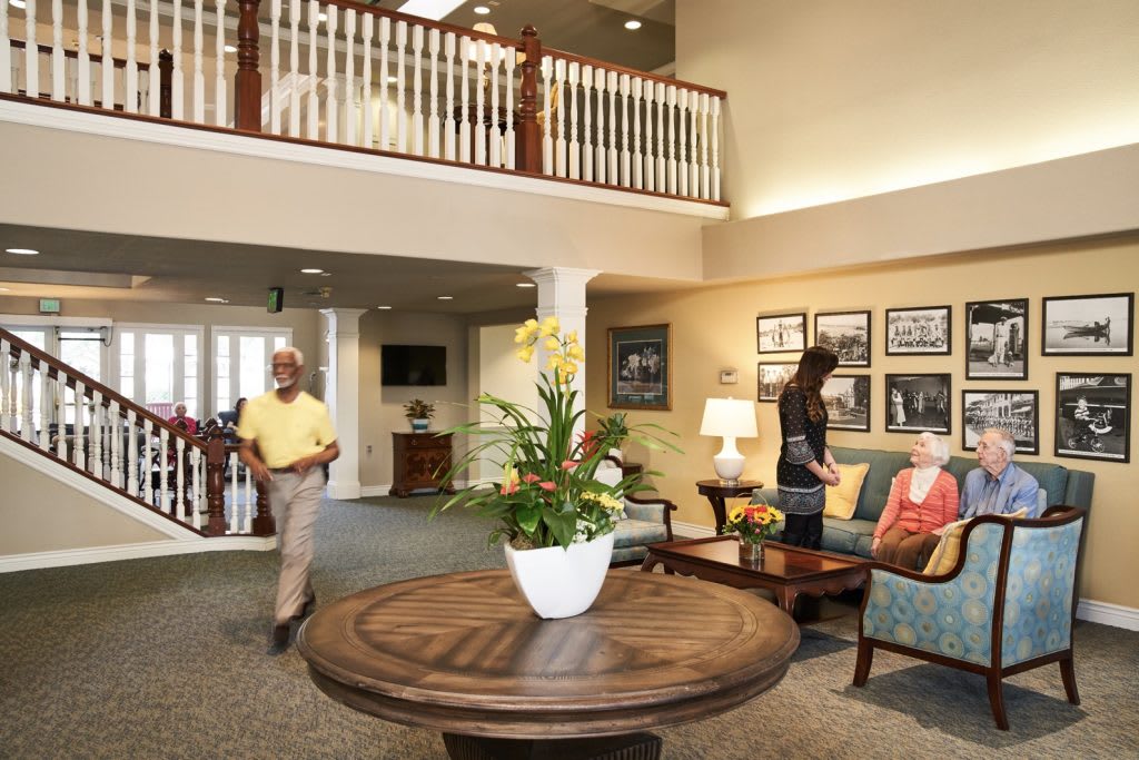 A welcoming lobby area with people interacting, featuring comfortable seating, decorative plants, and artwork on the walls.