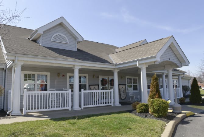 A suburban residential house with a large porch and well-maintained lawn.