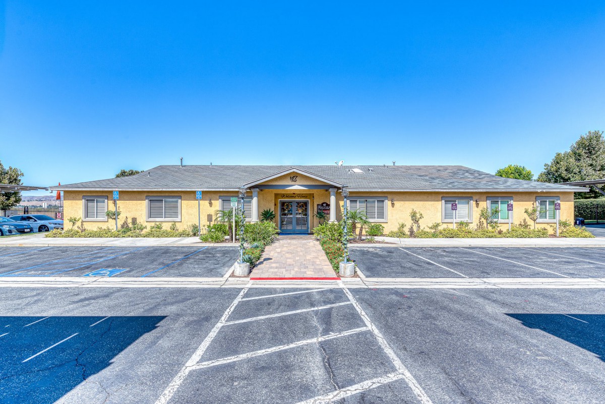 A single-story building with a parking lot and landscaped pathway leading to the entrance.