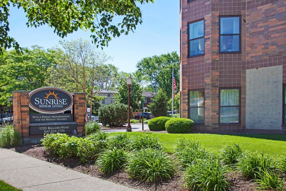 A view of a brick building with well-maintained landscaping and signage in front.