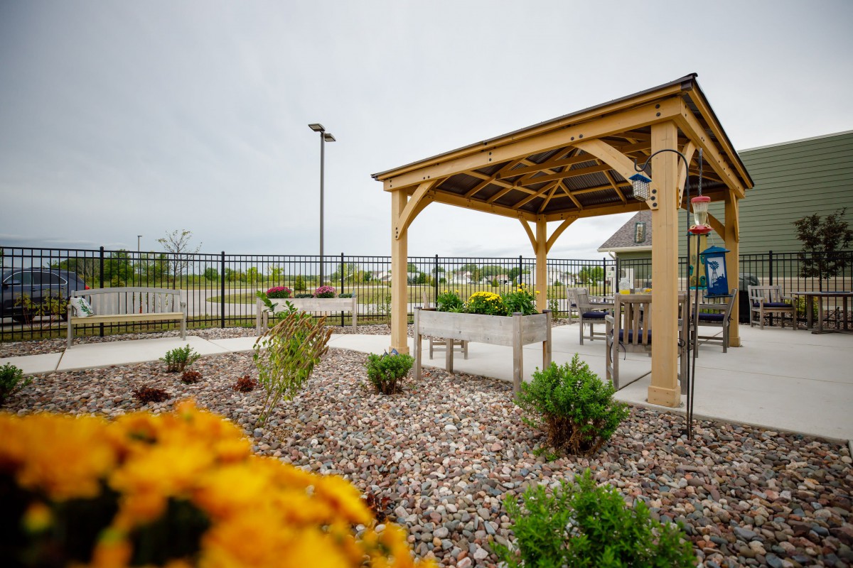 A serene garden with a wooden pergola, benches, and vibrant flowers.