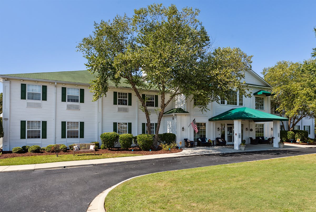 A charming hotel exterior with a green roof and surrounding trees.